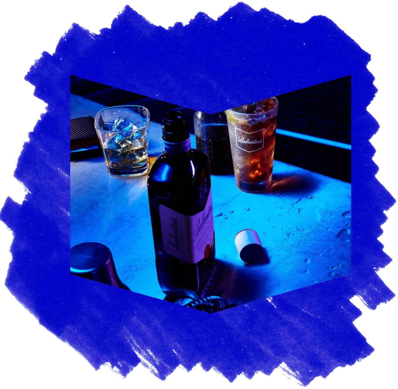 A bottle of Ballantine's whisky and glasses lit with blue light, on a blue textured background.